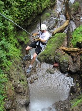 Mand i shorts, t-shirt og hjelm rapeller i en frodig kløft ved Arenal i Costa Rica.